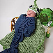 Jaiden joined the competition — help win amazing prizes! newborn, baby, sleeping, knitted_hat, blue_cloth, green_blanket, dinosaur_blanket, crocheted_toy, green_toy, baby_wrapped, infant, cute, studio_photo, white_background, peaceful, soft_texture, child, portrait, cozy, handmade