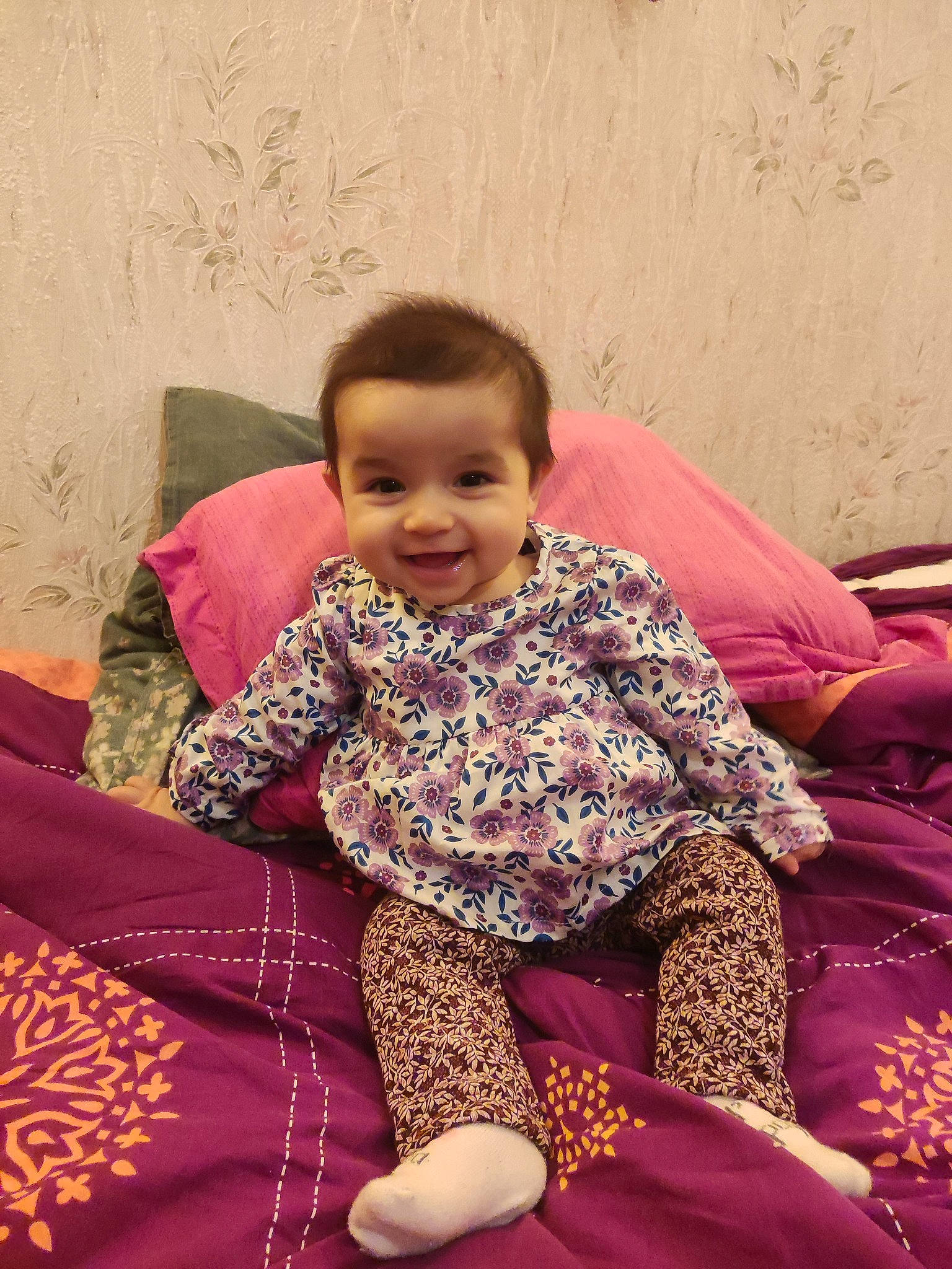 Hanaé participe au concours pour gagner de l'argent avec cette photo : baby_toddler_clothing, child, comfort, couch, flooring, happy, joint, joy, lap, leg, magenta, neck, pattern, person, pink, purple, shoulder, sitting, sleeve, smile