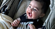 Iziah is registered to the contest to win money with this photo: baby, infant, stroller, blanket, clothing, nike, happy, smiling, face, person, child, indoors, cute, hand, portrait, expression, cozy, soft, comfortable, babywearing