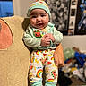 Iziah joined the competition — help win amazing prizes! baby, child, smiling, pajamas, hat, striped_socks, adult_hand, indoor, blurred_background, toys, poster, happy, colorful_clothing, infant, person, holding, cute, portrait, playful, cozy