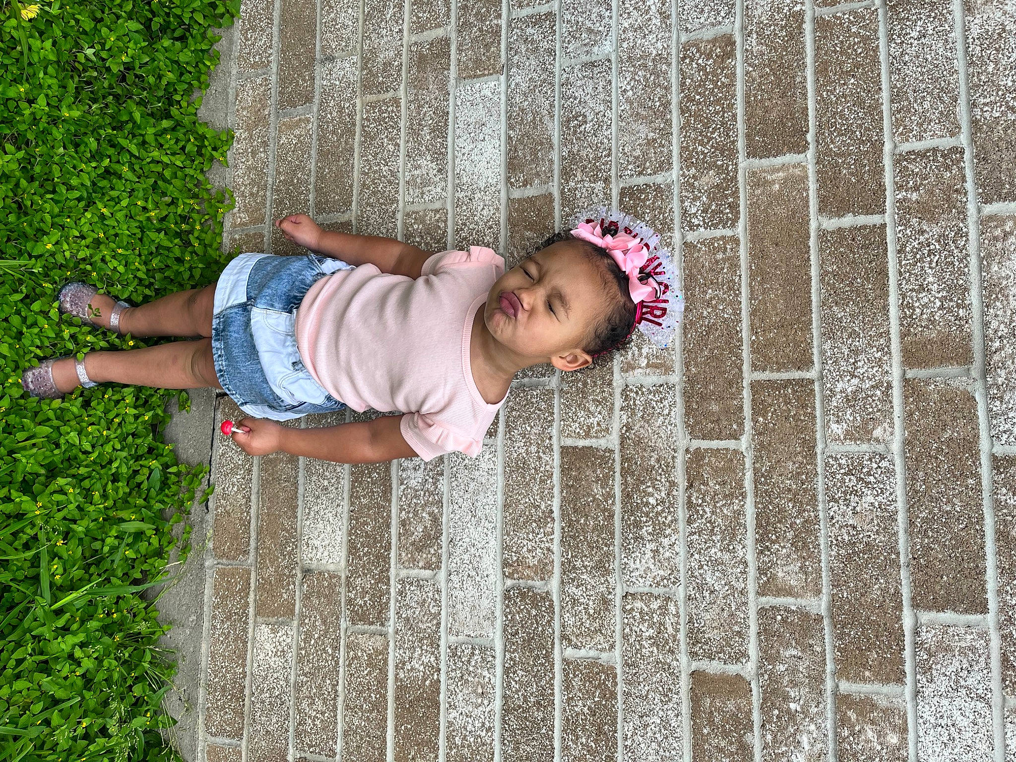 Adaline is registered to the contest to win money with this photo: baby, baby_toddler_clothing, child, fence, fun, grass, happy, leisure, magenta, pattern, people_in_nature, person, plant, play, sitting, spring, t_shirt, toddler, tree