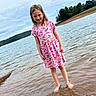 barefoot, child, clouds, colorful_clothing, girl, hillside, lake, nature, outdoor, pink_dress, portrait, ripples, shore, shoreline, sky, smiling, standing, summer, trees, water
