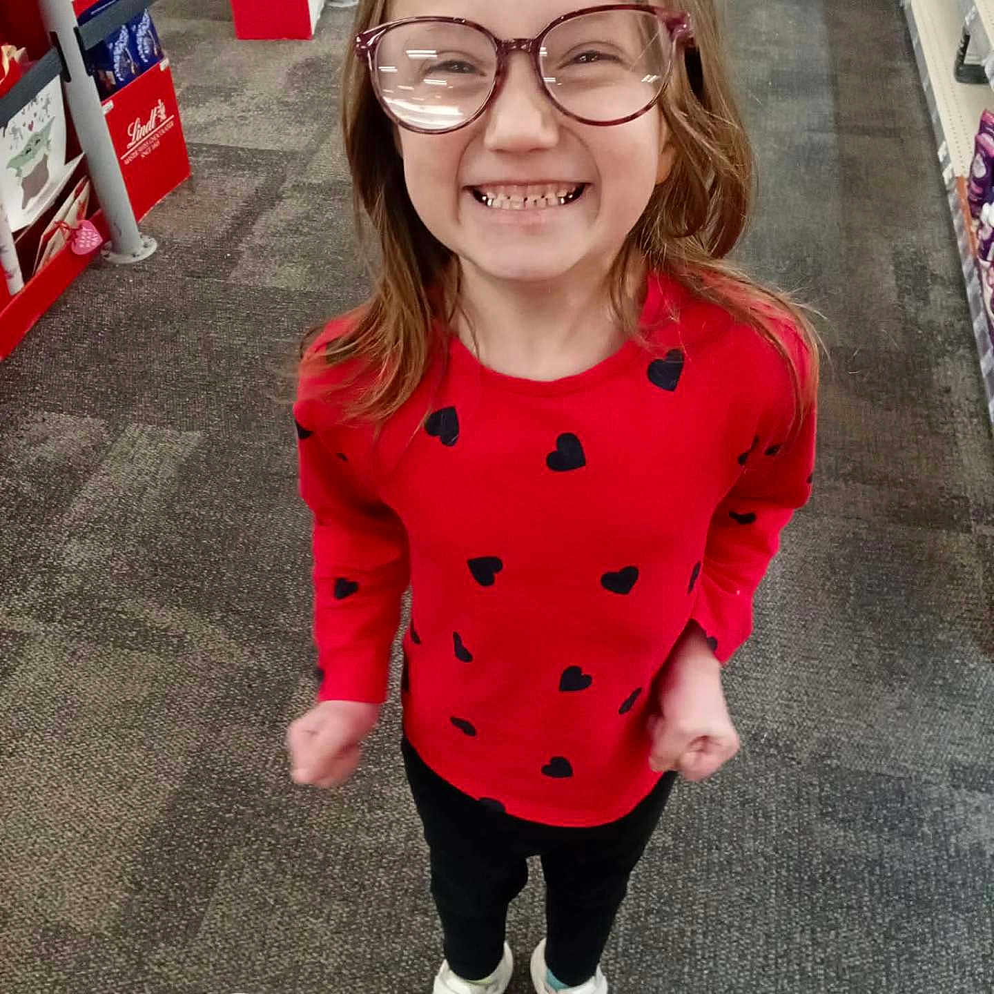 Brylynn Ann Dawn is registered to the contest to win money with this photo: candid, carpet, casual, child, eyewear, full_body, girl, glasses, happy, heart_pattern, portrait, red_shirt, retail, shelves, shopping, smile, sneakers, standing, store_aisle, teeth