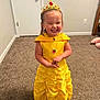 child, girl, princess, yellow_dress, crown, smiling, jewelry, necklace, earrings, carpet, indoor, happy, cute, costume, dress_up, standing, room, door, wall, playful