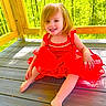 child, toddler, girl, smiling, portrait, red_dress, outdoor, wooden_deck, forest, sunlight, nature, blonde_hair, blue_eyes, seated, happy, summer, playful, face, person, backyard