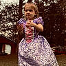Americus Leighann is registered to the contest to win money with this photo: child, girl, toddler, dress, purple_dress, outdoor, backyard, forest, trees, pine_trees, grass, shed, portrait, standing, fashion, costume, princess, hair_bow, smiling, nature