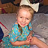 Americus Leighann joined the competition — help win amazing prizes! child, girl, smiling, portrait, indoors, bedroom, bed, blanket, dress, colorful_clothing, hair_bow, white_bow, brown_hair, face, hands, sitting, happy, plush_toy, cozy, photography