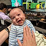 baby, smiling, striped_clothing, blue, infant, hand, auditorium, theater, stage, screen, crowd, seated_people, happy, person, portrait, indoor, blanket, light, event, audience
