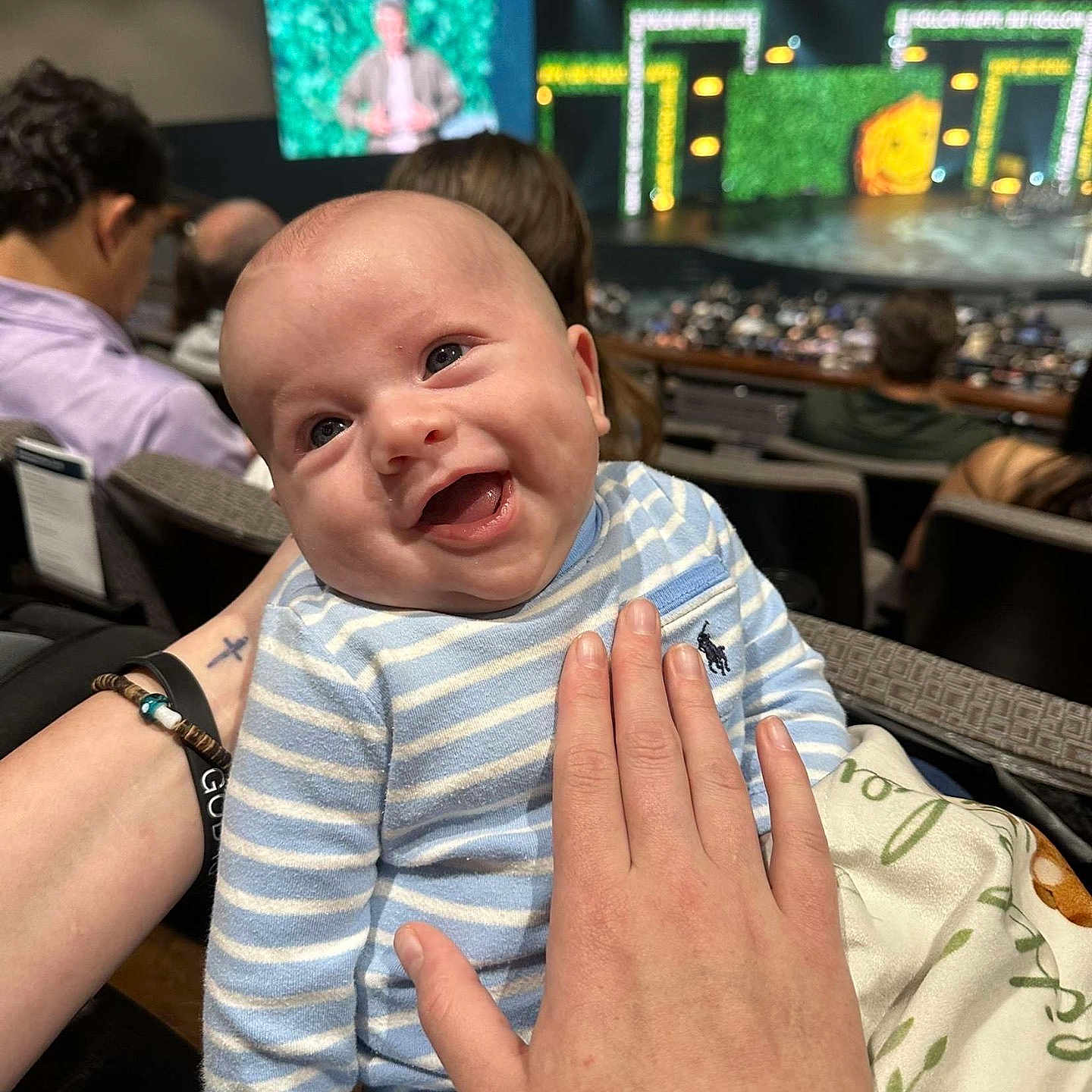 Acen joined the competition — help win amazing prizes! audience, auditorium, baby, blanket, blue, crowd, event, hand, happy, indoor, infant, light, person, portrait, screen, seated_people, smiling, stage, striped_clothing, theater