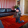 Aaron participe au concours pour gagner de l'argent avec cette photo : beanie, blue_shoes, carpet, child, couch, doorway, floor, furniture, home, indoor, jacket, living_room, motion, painting, person, playful, potted_plant, smiling, striped_wall, toddler