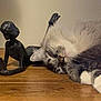 cat, sleeping, wooden_surface, sculpture, statue, indoor, cozy, relaxing, fluffy, gray_cat, white_paws, art, decor, quiet, peaceful, table, resting, feline, domestic_cat, closeup