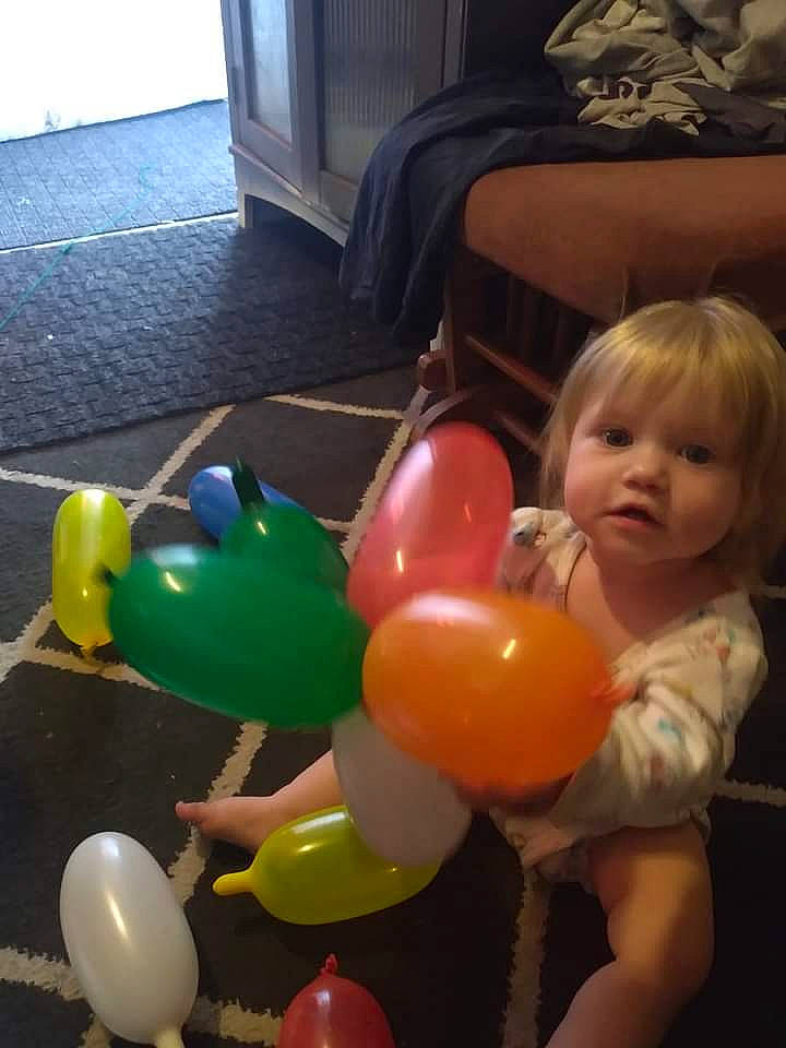 Elizabeth is registered to the contest to win money with this photo: balloon, child, comfort, couch, event, flooring, fun, happy, leisure, living_room, party, party_supply, person, picture_frame, room, sitting, television, toddler, toy