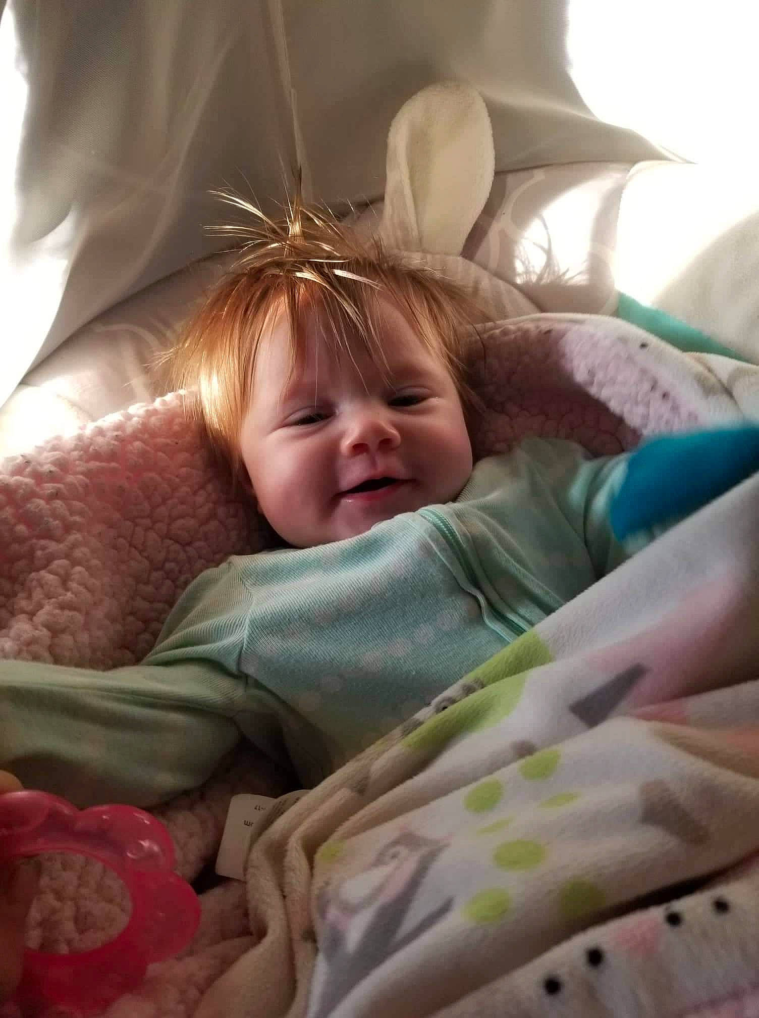 Elizabeth is registered to the contest to win money with this photo: baby, bed, bedding, blond, brown_hair, child, comfort, eye, face, fun, hair, happy, head, iris, lamp, linens, person, pink, skin, smile