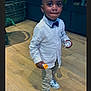 toddler, child, boy, indoor, wooden_floor, white_shirt, bow_tie, sneakers, pants, standing, holding, container, cute, portrait, person, shoes, looking, expression, fashion, casual