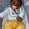 Emerie is registered to the contest to win money with this photo: baby, infant, pacifier, baby_chair, yellow_pants, purple_sock, white_sock, hair_bows, cute, child, indoor, clothing, bib, seated, portrait, person, comfort, baby_accessory, soft_cushion, relaxed