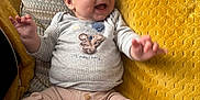Roman is registered to the contest to win money with this photo: baby, smiling, happy, couch, pillow, yellow_pillow, patterned_pillow, baby_clothes, bear_design, sitting, infant, cute, indoors, child, cozy, plush, hand_gesture, portrait, comfort, soft_furniture