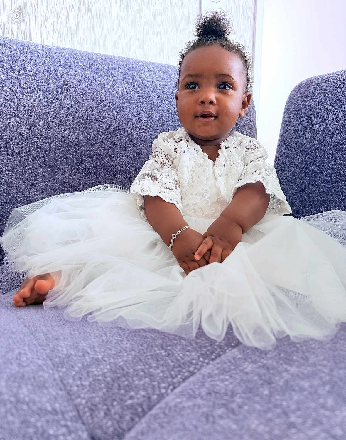 Jalia a rejoint le concours — aidez-le/la à gagner de superbes lots ! baby, child, white_dress, lace, bracelet, purple_couch, sitting, curly_hair, indoor, portrait, smiling, cute, infant, hands, feet, soft_texture, cozy, young, person, tulle