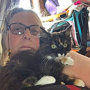 Juana joined the competition — help win amazing prizes! woman, cat, glasses, indoor, furniture, bag, window, curtain, tortoiseshell_cat, pet, face, person, hair, whiskers, eyes, fur, arm, clothing, home, relaxing
