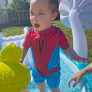 Aidan is registered to the contest to win money with this photo: backyard, child, curious, fun, grass, inflatable_pool, outdoor, person, playing, pool, small_pool, spiderman, summer, sunlight, swimsuit, toddler, toy, water, wet_hair, yellow_inflatable