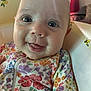 baby, baby_clothes, child, close_up, colorful, cute, eyes, face, floral_pattern, happy, head, indoor, infant, onesie, person, seat, skin, smiling, tongue, young_child
