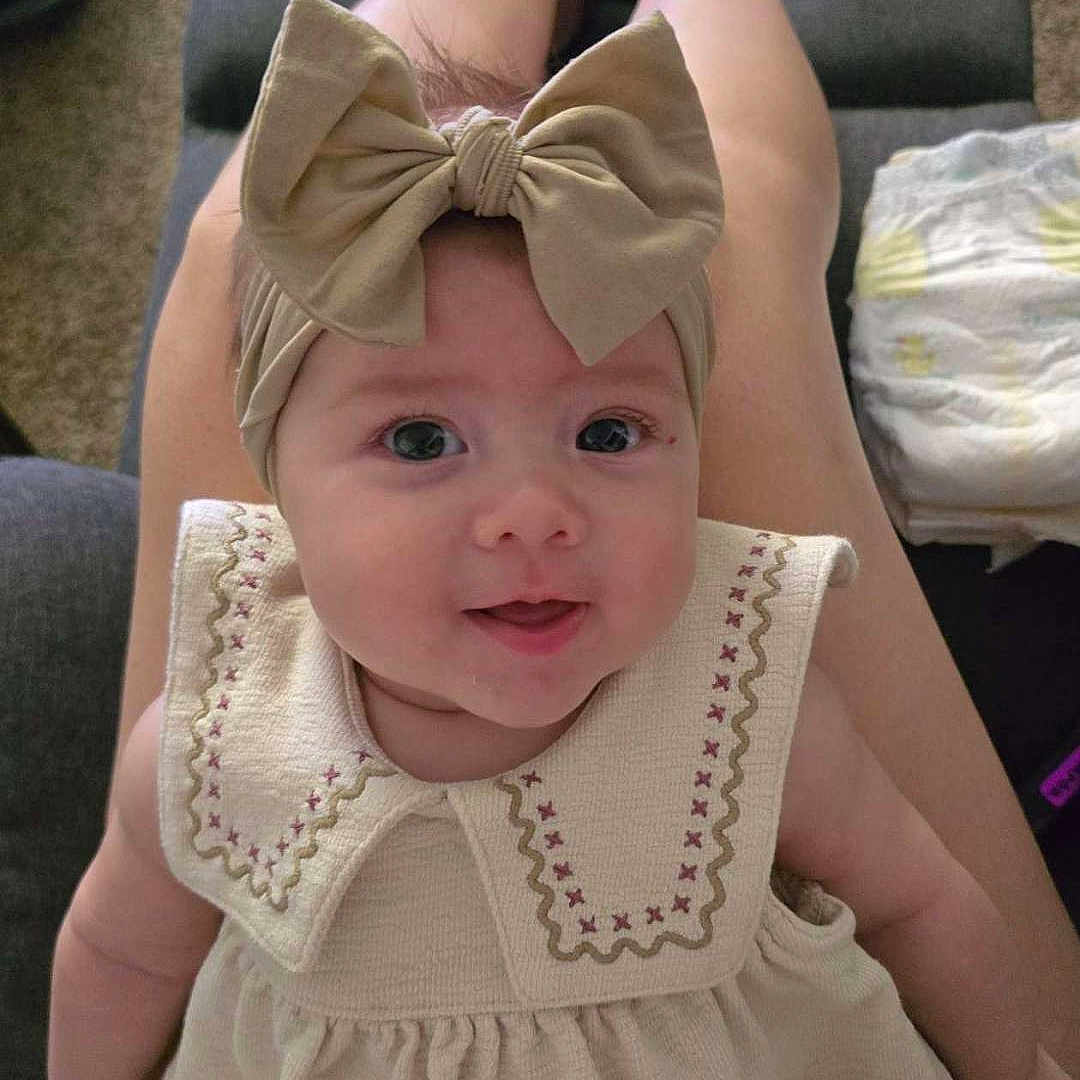 Freya joined the competition — help win amazing prizes! baby, child, headband, bow, dress, smiling, legs, feet, toy, shopping_cart, carpet, indoor, person, cute, happy, infant, home, play, seated, portrait