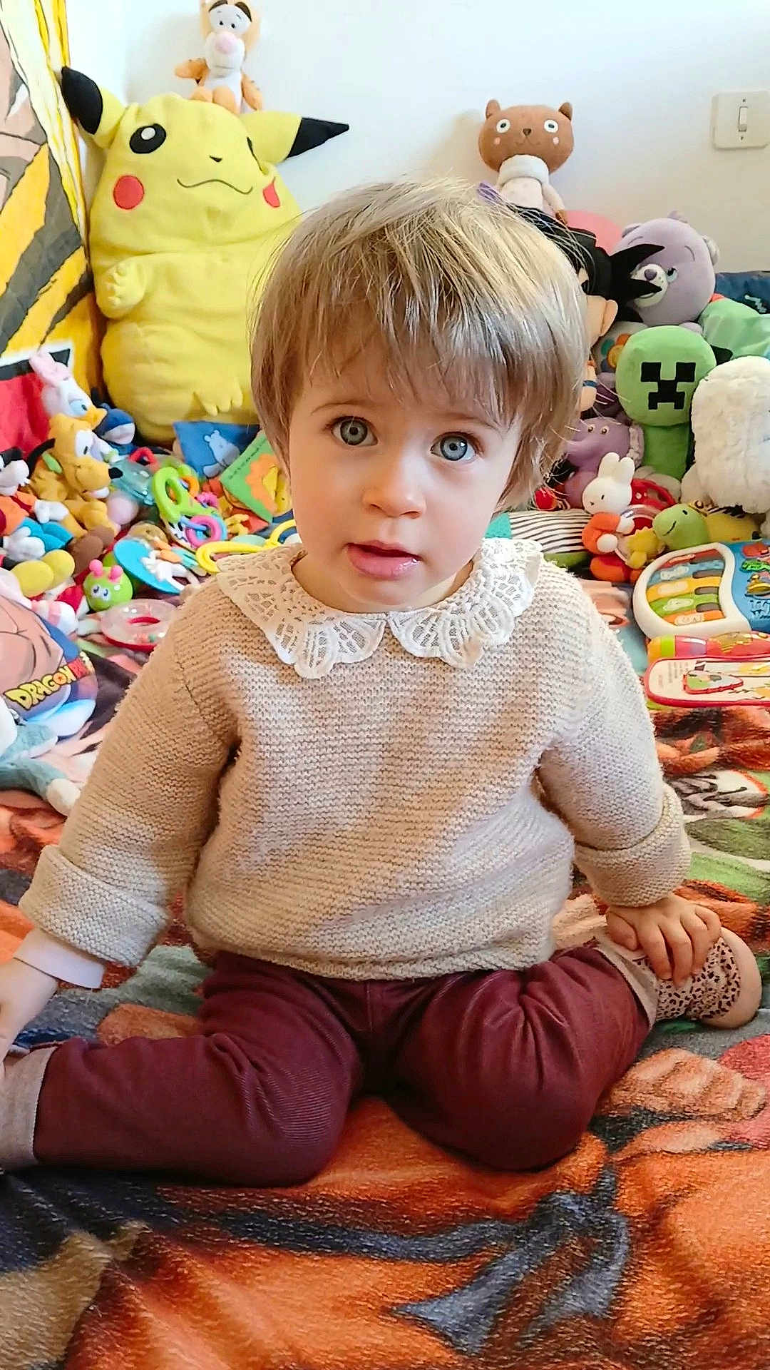 Adélaïde participe au concours pour gagner de l'argent avec cette photo : blanket, casual_clothing, child, collar, colorful, curious_eyes, cute, indoors, knitted_sweater, pikachu, playroom, plush_toys, portrait, relaxed, sitting, soft_toys, stuffed_animals, toddler, toy_collection, young_child