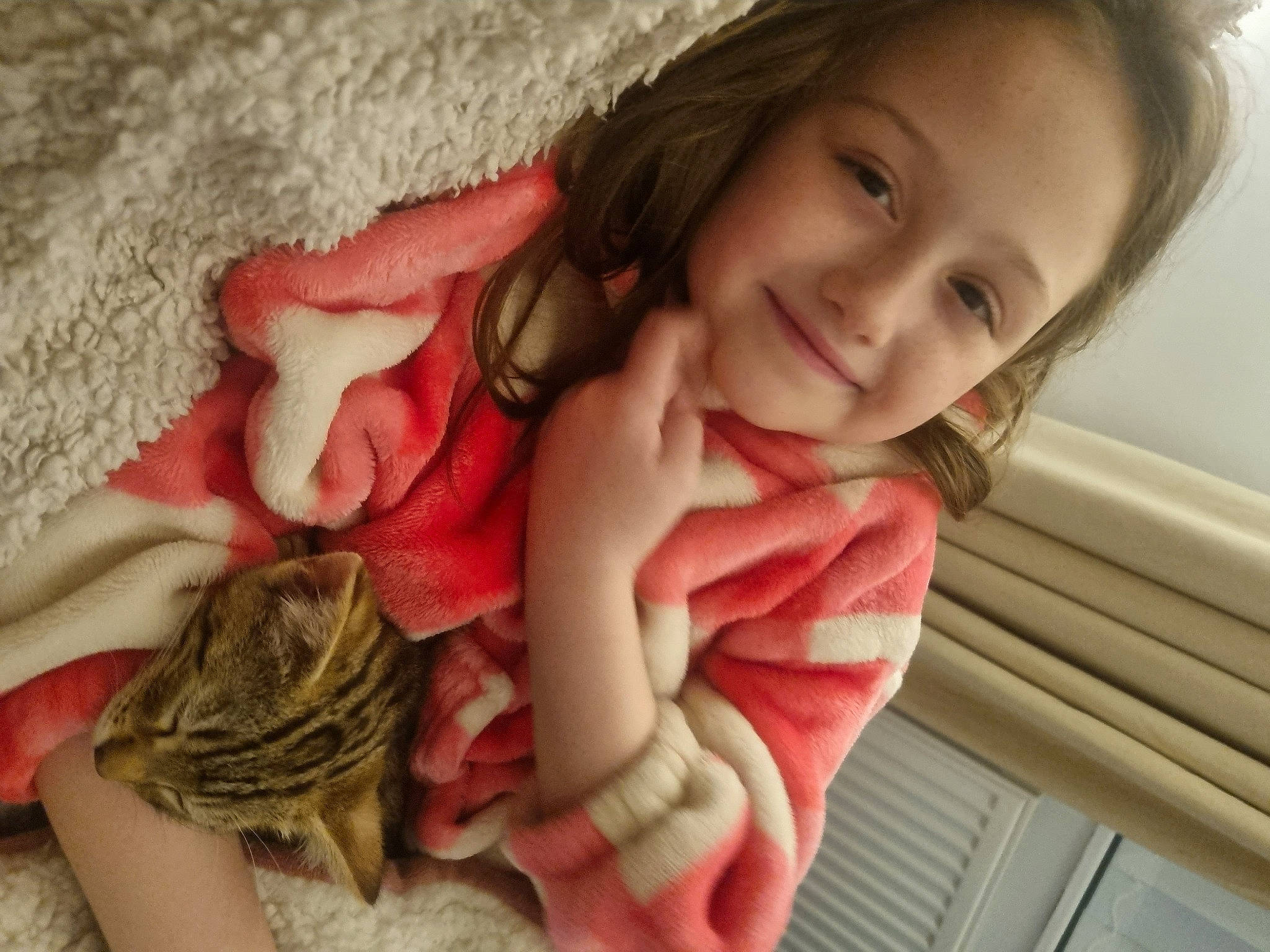 Oliver is registered to the contest to win money with this photo: arm, brown_hair, comfort, elbow, eyelash, finger, gesture, happy, human_leg, lip, long_hair, nail, neck, sitting, skin, smile, thigh, thumb, toddler, wood