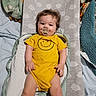 baby, child, pacifier, yellow_onesie, changing_pad, blanket, bed, infant, cute, smiling, soft_lighting, indoors, resting, clothing, person, baby_bedding, portrait, comfort, happy, toddler