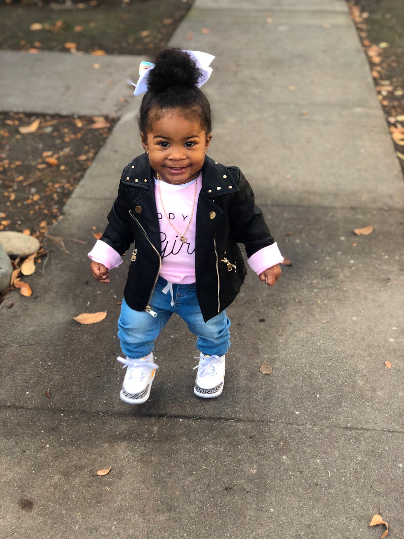 Jayla is registered to the contest to win money with this photo: asphalt, boot, child, city, eye, face, fun, happy, jacket, joy, pedestrian, person, recreation, road, road_surface, shadow, sidewalk, sitting, smile, street