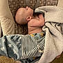 baby, sleeping, blanket, baby_seat, carpet, foot, water_bottle, indoor, soft_texture, pattern, child, infant, rest, comfort, napping, person, head, skin, clothing, home