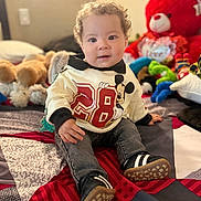 Lucas Planchez is registered to the contest to win money with this photo: bedspread, child, cozy, curly_hair, cute, happy, home, indoor, jeans, mickey_mouse, playful, portrait, seated, smiling, sneakers, stuffed_animals, sweater, teddy_bear, toddler, toy
