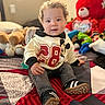 bedspread, child, cozy, curly_hair, cute, happy, home, indoor, jeans, mickey_mouse, playful, portrait, seated, smiling, sneakers, stuffed_animals, sweater, teddy_bear, toddler, toy