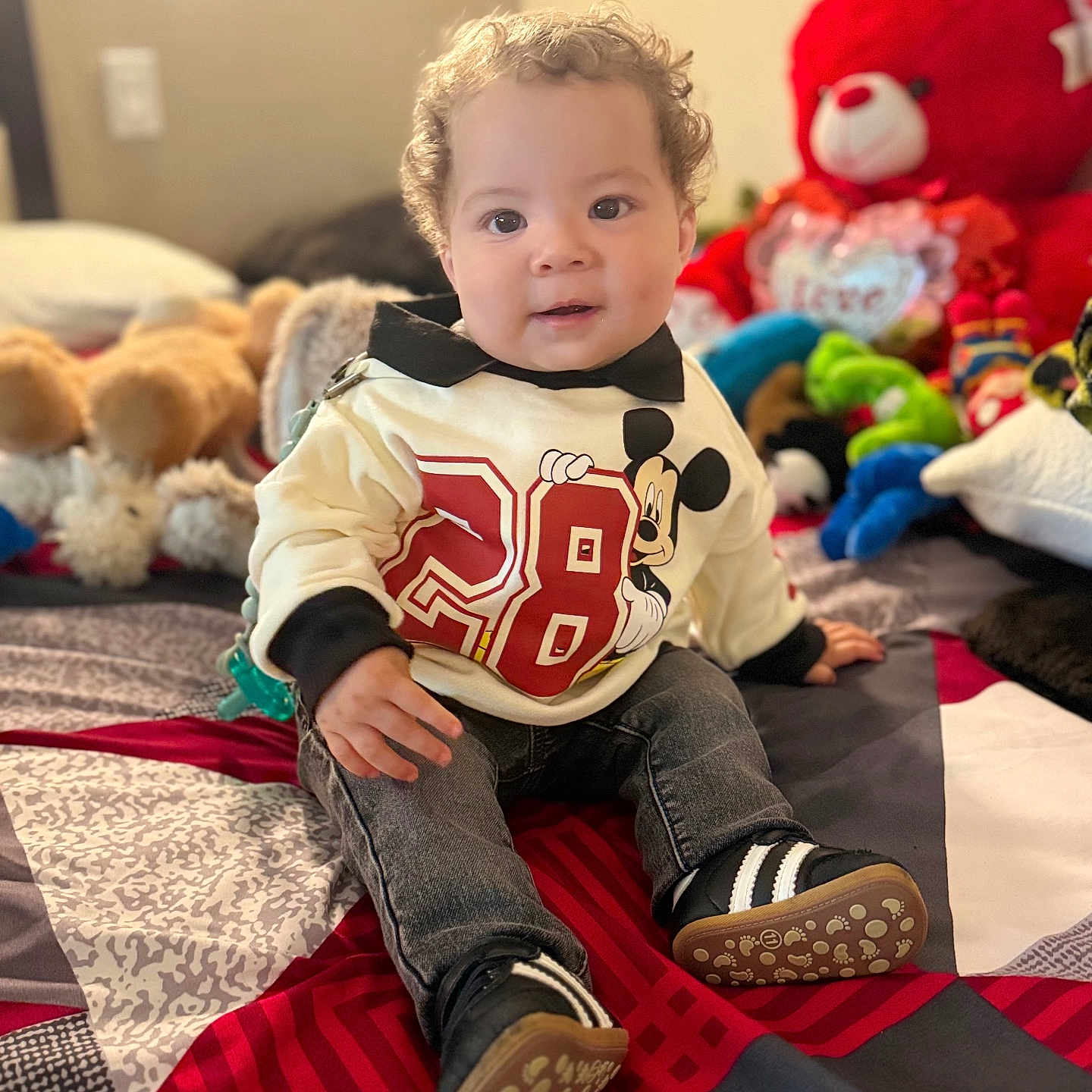 Lucas Planchez is registered to the contest to win money with this photo: bedspread, child, cozy, curly_hair, cute, happy, home, indoor, jeans, mickey_mouse, playful, portrait, seated, smiling, sneakers, stuffed_animals, sweater, teddy_bear, toddler, toy