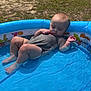 Lakelynn is registered to the contest to win money with this photo: baby, child, pool, inflatable_pool, water, grass, outdoor, sunlight, summer, relaxing, infant, sleeveless_shirt, barefoot, skin, head, legs, feet, small_pool, reclining, daytime