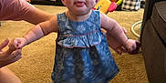Lakelynn is registered to the contest to win money with this photo: baby, child, girl, blue_dress, pink_bow, carpet, living_room, toy, television, adult_hand, photo_frame, furniture, indoor, smile, standing, sandals, person, cute, home, helping_hand