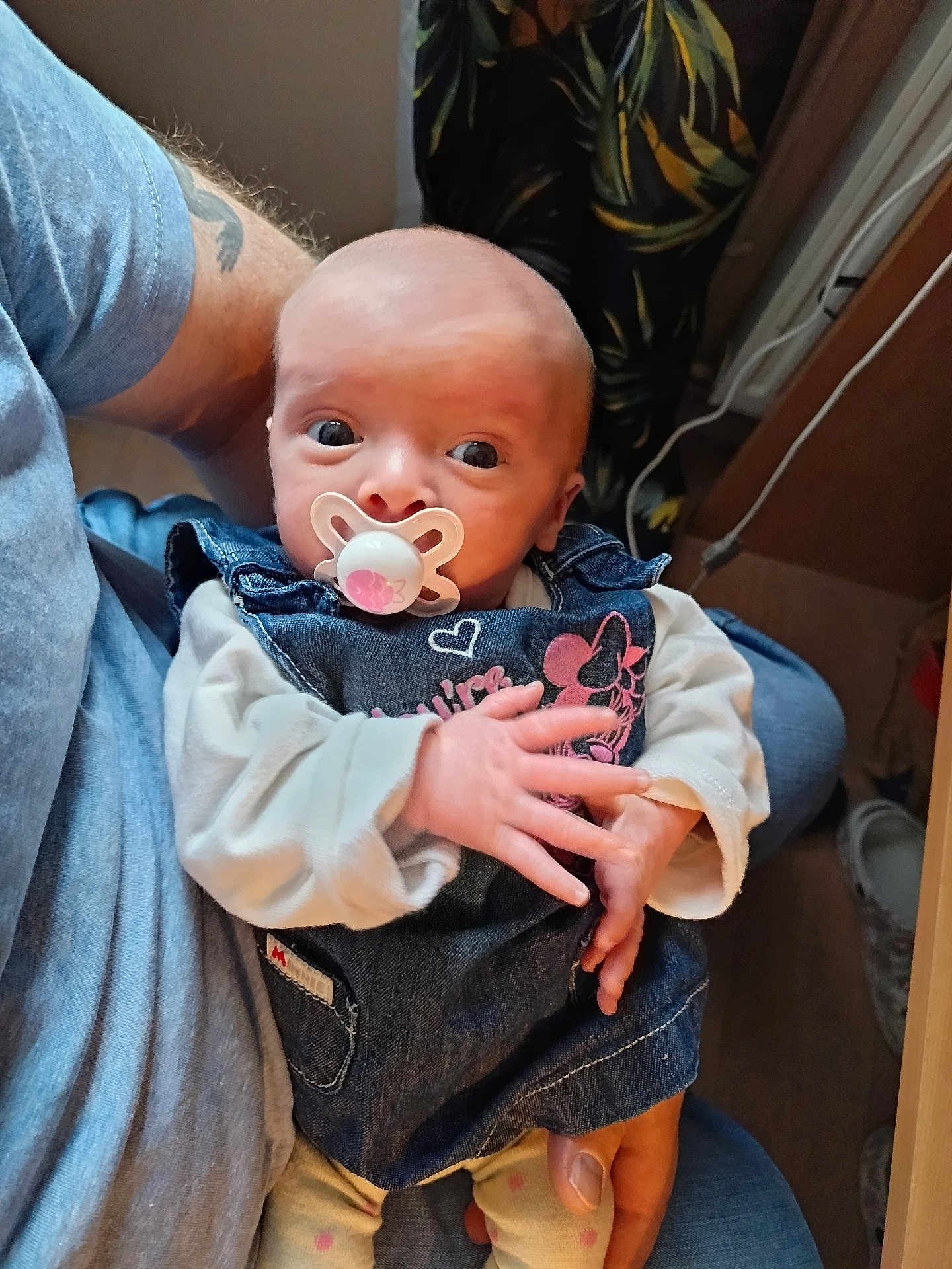 Zoé participe au concours pour gagner de l'argent avec cette photo : baby, pacifier, adult, hand, denim_dress, indoor, person, clothing, holding, sitting, floor, shoe, tattoo, skin, long_sleeve, denim, cute, infant, casual, portrait