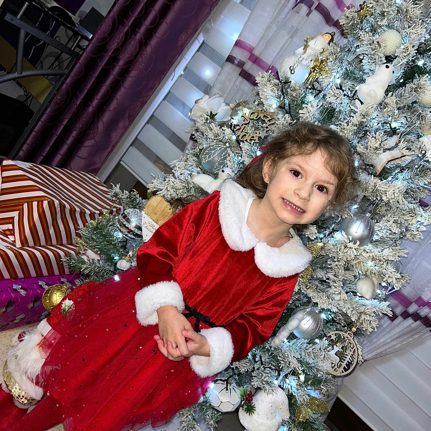 Camélya participe au concours pour gagner de l'argent avec cette photo : celebration, child, christmas_ornaments, christmas_tree, curtains, cute, decorations, festive, girl, happy, holiday, holiday_season, indoor, portrait, presents, red_dress, smile, sparkle, white_tree, winter