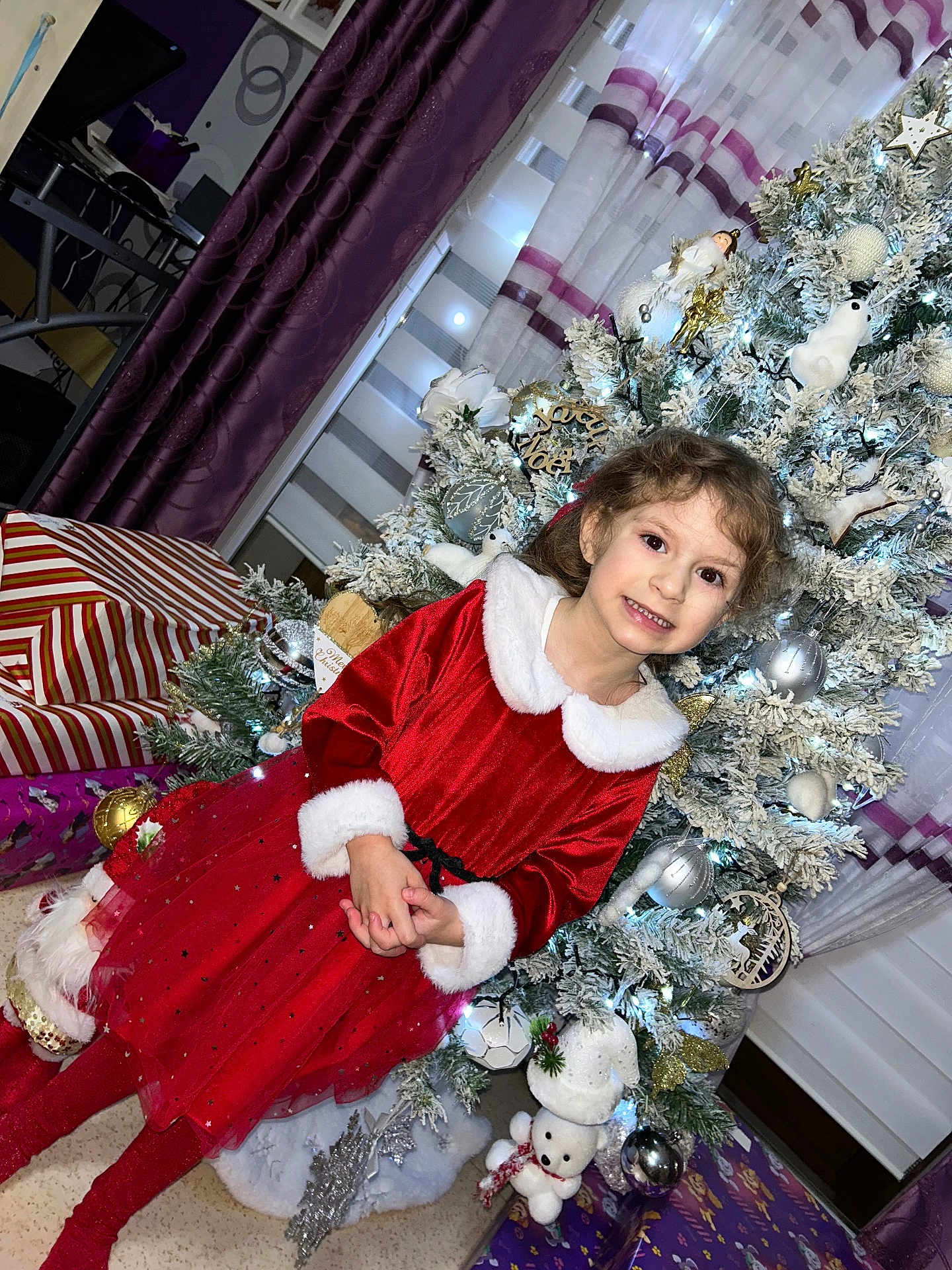 Camélya participe au concours pour gagner de l'argent avec cette photo : child, girl, christmas_tree, holiday, red_dress, smile, presents, decorations, indoor, festive, curtains, christmas_ornaments, happy, celebration, winter, holiday_season, white_tree, sparkle, cute, portrait