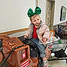 toddler, child, green_bow, coin_operated_ride, horse_ride, shopping_cart, store_interior, casual_clothing, pink_jacket, jeans, sneakers, indoor, curious_expression, toy_ride, retail_environment, white_wall, door, floor, shopping_bags, portrait