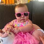 Gianna is registered to the contest to win money with this photo: baby, child, pink_sunglasses, plush_toy, unicorn, dress, pink_dress, couch, indoor, cute, chubby, toddler, hands, face, person, soft_toy, sitting, funny, stylish, home