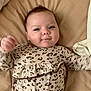 baby, infant, bed, blanket, leopard_print, clothing, cute, face, smile, lying_down, child, young, person, sleepwear, bedroom, soft, happy, skin, head, pajamas