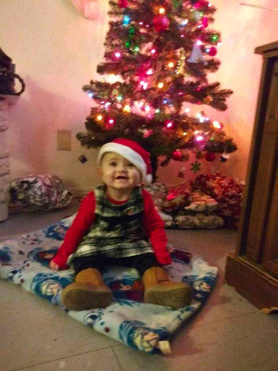 Alia is registered to the contest to win money with this photo: baby_toddler_clothing, child, christmas, christmas_decoration, christmas_eve, christmas_lights, christmas_ornament, christmas_tree, door, flooring, headwear, holiday, holiday_ornament, home, interior_design, joy, lighting, living_room, ornament, person