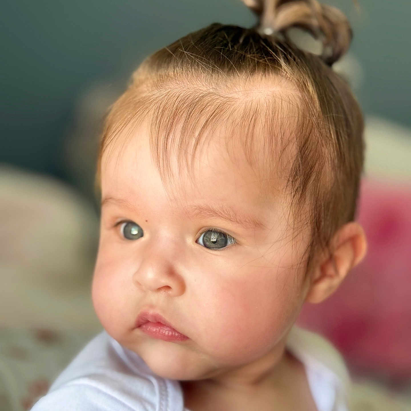 Kilah is registered to the contest to win money with this photo: baby, blurry_background, cheeks, child, closeup, clothing, cute, expression, eyes, face, hair, indoors, infant, person, ponytail, portrait, skin, soft_light, white_shirt, young