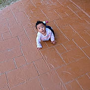 Xana is registered to the contest to win money with this photo: baby, child, crawling, outdoor, patio, brick_floor, hose, plant, garden, curious, looking_up, concrete, sidewalk, greenery, person, young_child, casual_clothing, daylight, cute, small