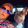 man, dog, french_bulldog, car, selfie, sunglasses, hat, seat, window, casual, expression, indoor, pet, companion, portrait, vehicle_interior, reflection, plaid_shirt, tongue_out, daylight