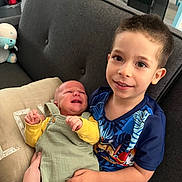 Elyo a rejoint le concours — aidez-le/la à gagner de superbes lots ! baby, boy, child, couch, crying, face, hand, home_interior, infant, living_room, person, pillow, plush_toy, sibling, smile, sitting, toy, upholstery, young_child, youngster