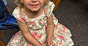 Everleigh joined the competition — help win amazing prizes! blue_eyes, blue_sneaker, carpet, child, curly_hair, cute, floor, floral_dress, footwear, girl, happy, indoor, person, playful, portrait, sitting, smiling, toy, wooden_chair, young_child