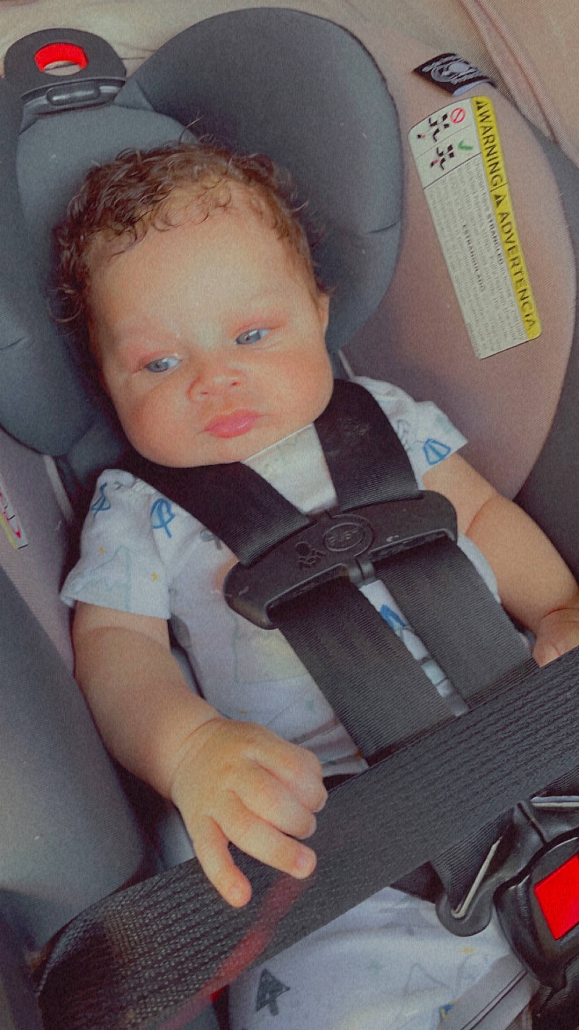 Esther is registered to the contest to win money with this photo: arm, auto_part, automotive_design, baby, baby_carriage, baby_in_car_seat, baby_products, baby_toddler_clothing, car_seat, chair, cheek, child, comfort, finger, head_restraint, person, seat_belt, sitting, skin, toddler