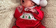 Kennedy is registered to the contest to win money with this photo: baby, infant, red_clothing, polka_dots, santa_hat, christmas, holiday, blanket, soft_texture, yawning, cute, sleepwear, festive, cozy, lying_down, hand, footed_pajamas, toddler, indoors, portrait
