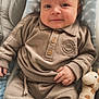 baby, infant, child, plush_toy, giraffe_toy, socks, clothing, beige_outfit, baby_seat, smile, face, hand, cute, soft_texture, cozy, indoor, portrait, comfort, small_scratches, relaxed